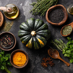 Kabocha squash with cooking ingredients and spices on dark background