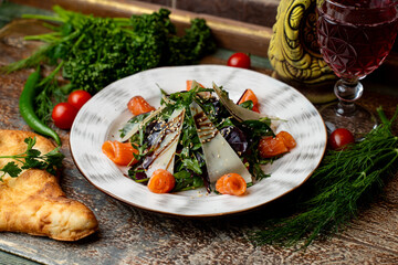 A beautifully arranged plate featuring fresh Georgian dishes, including herbs, salmon, and vegetables, perfectly paired with a glass of red wine. A feast for the senses in a warm restaurant setting