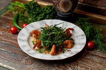 Freshly prepared Georgian dishes are beautifully arranged at a cozy restaurant. The plate features grilled shrimp and a vibrant salad with herbs, showcasing rich flavors and colorful presentation
