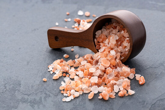 Coarse pink Himalayan salt spilled from a wooden measuring spoon - Powered by Adobe