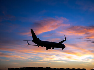 Passenger airliner silhouette landing at Seville Airport during sunset