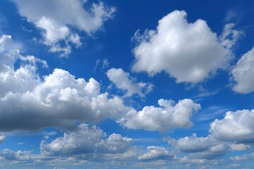 Fototapeta premium Bright open sky filled with puffy white and gray cumulus clouds on a clear blue day