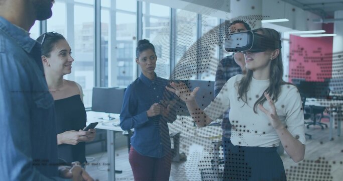 Testing woman wearing virtual reality headset gesturing in open office with smartphone, copy space