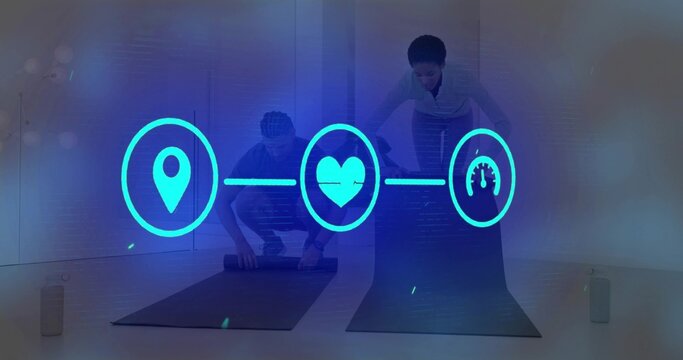 Rolling partners in athletic clothes preparing yoga mats at yoga studio with cyan holographic icons - Powered by Adobe