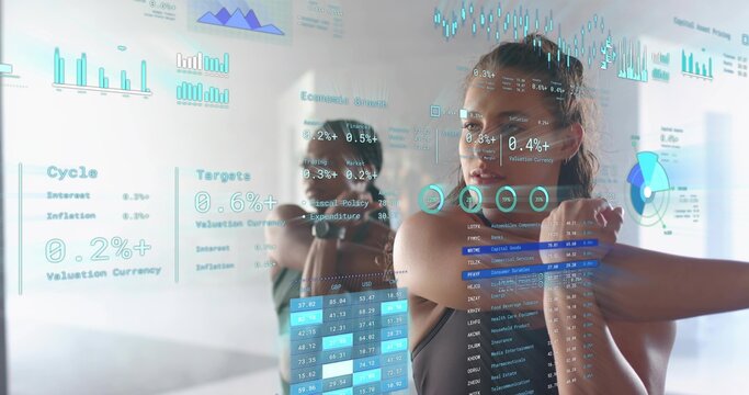Adult woman stretching in bright fitness studio, wearing dark sports top with mirror and AR charts