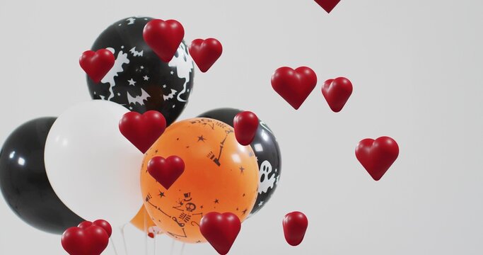 Naklejki Floating Halloween balloon cluster in gray studio, showing skull prints, red hearts, copy space