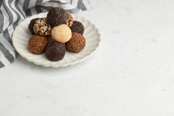 Typical Brazilian sweet brigadeiro. A heap of assorted flavors of candies on a white table with copy space