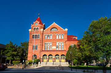 The historic Paul Laxalt State Building, a red brick Romanesque building with a clock tower, in Carson City, Nevada. The former post office is seen on a sunny day with a clear blue sky