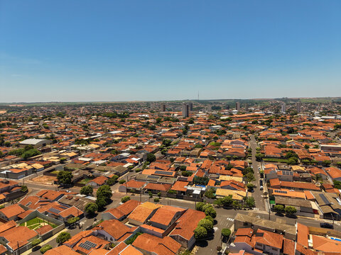 Aerial view of a cityscape featuring a dense network of redtiled rooftops under a clear blue sky, showcasing urban sprawl and architectural uniformity - Powered by Adobe
