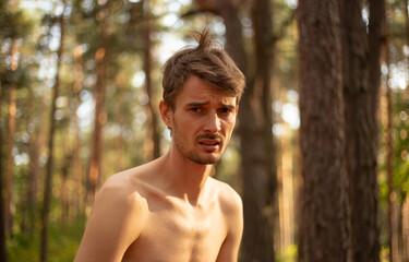 a worried  upset guy in the woods with a bare chest