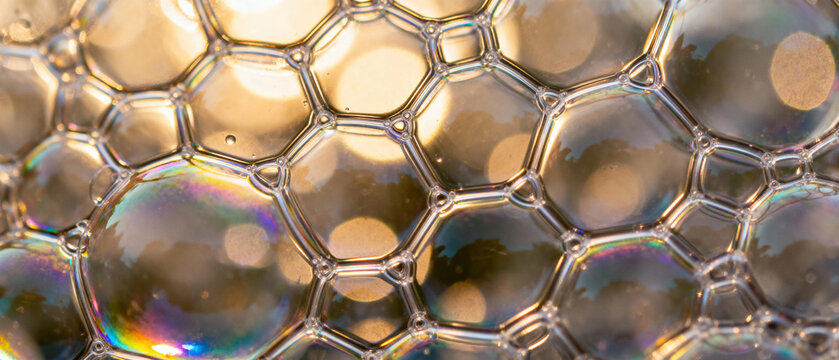 Close-up of iridescent soap bubbles forming a honeycomb pattern with reflective surfaces and soft bokeh background - Powered by Adobe