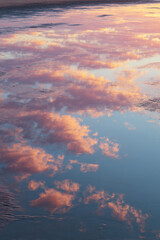 Fototapeta premium Soft Reflections of Sunrise Clouds on Wet Sand, Mirror-Like Shore with Pastel Glow – great for inspirational wall art