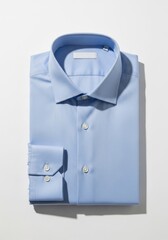 A neatly folded light blue dress shirt with white buttons on a white background featuring a structured collar and cuffs