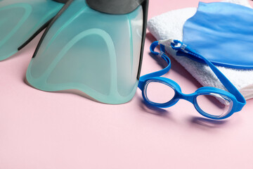 Flippers, towel, goggles and swim cap on pink background, closeup. Space for text © New Africa
