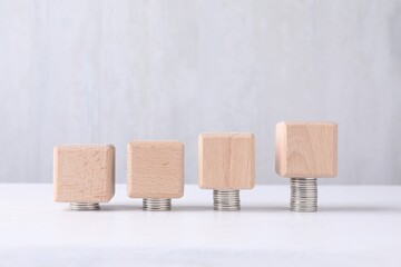 Blank wooden cubes and stacked coins on white table. Mockup for design