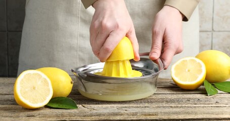 Woman squeezing juice from lemon with juicer at table, closeup - Powered by Adobe