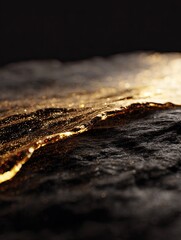 Dark textured surface with a bright, golden edge against a dark background