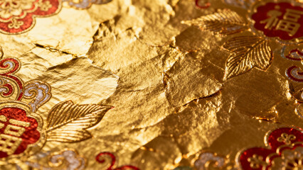 Close-up of ornate golden fabric with red and white floral patterns and Chinese characters