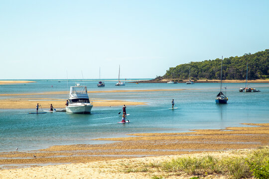 Stand up paddlers and boats on Round Hill Creek, the Town of 1770, Queensland.