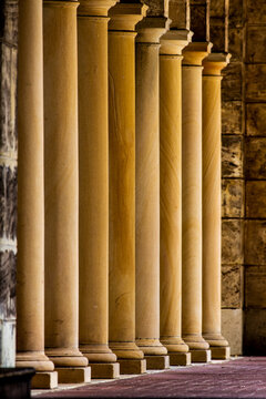 A line of old stone pillars at front of stone walled building.