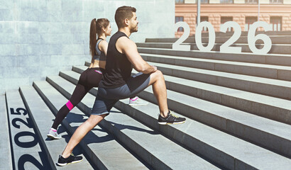 Two fitness enthusiasts are exercising on a set of stone steps. They are stretching, focusing on their fitness goals, with the years 2025 and 2026 displayed prominently in the background.