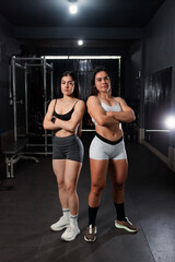Fototapeta premium Two beautiful girls in sportswear showing off their muscles at the gym.