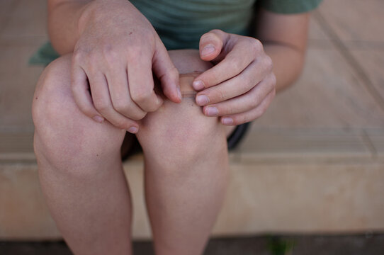 Close up of child's hands putting plaster on knee
