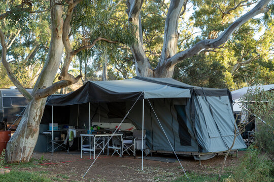 Caravan with awning surrounded by gum trees.