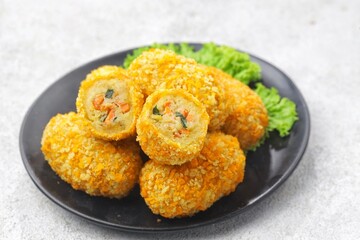Kroket kentang. Croquettes are lumps of finely mashed potatoes filled with seasoned minced meat and mixed with vegetables such as carrots or green beans. The croquettes are coated with beaten egg and 