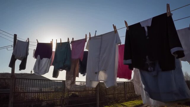 Ropa de colores variados sec&aacute;ndose al sol en un tendedero exterior en un d&iacute;a soleado.