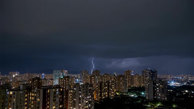 Impresionante vista nocturna de una ciudad con rascacielos iluminados bajo un cielo tormentoso y un rayo impactante.