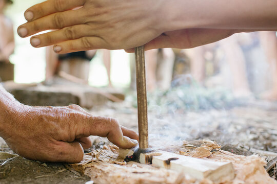 Two hands engaged in flint knapping to create fire.