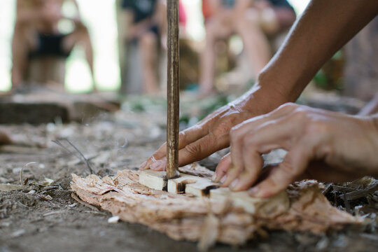 Two hands engaged in flint knapping to create fire.