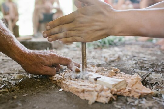 Two hands engaged in flint knapping to create fire.