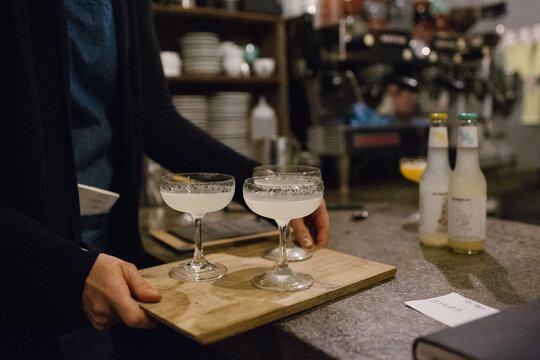 Three stemmed glasses of cocktail served on a wooden board