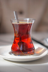 Warm turkish tea served in elegant glass cup on a white plate