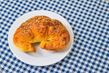 Close up view of one cheese croissant on white plate. isolated on the napkin background. High angle, above, flat lay. copy space, empty, free, negative, text, design.