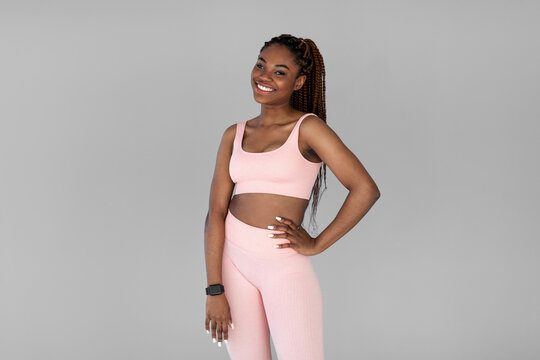 A lovely young black female is smiling while posing in a comfy sports outfit on a grey background. She represents a healthy lifestyle and exudes confidence and positivity. - Powered by Adobe