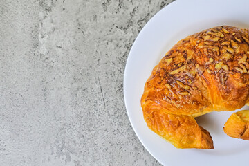 Top view of one cheese croissant on white plate. close up. grey or gray cement on the background. High angle, above, flat lay. half. copy space, empty, free, negative, text, design.