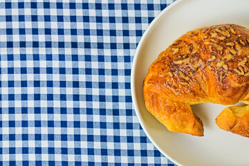 Top view of one cheese croissant on white plate. close up. isolated on the napkin background. High angle, above, flat lay. copy space, empty, free, negative, text, design.