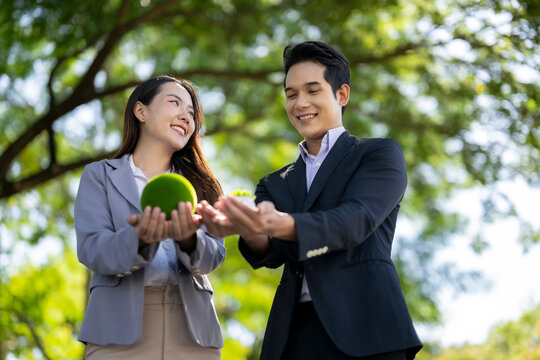 Business couple holding green sphere representing sustainability
