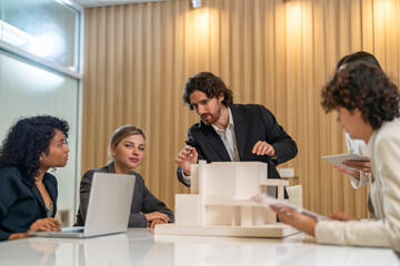 Architects engineers collaborating on building design project in modern office, diverse team of professionals female muslim architect and male engineers discussing architectural model of structure