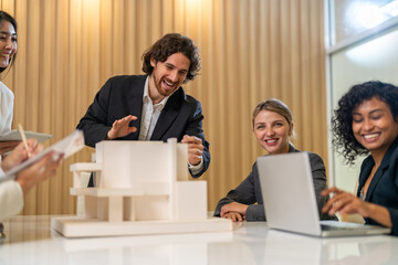 Architects engineers collaborating on building design project in modern office, diverse team of professionals female muslim architect and male engineers discussing architectural model of structure