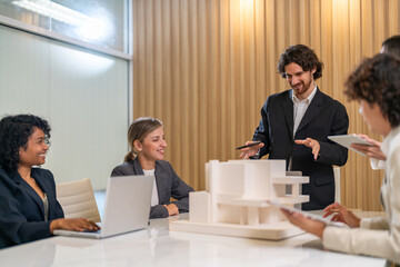 Architects engineers collaborating on building design project in modern office, diverse team of professionals female muslim architect and male engineers discussing architectural model of structure