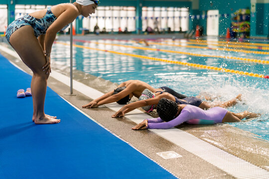 Instructor teaching children swimming lessons in pool