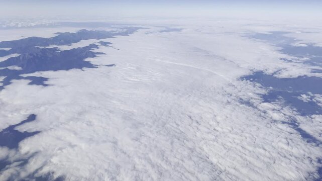 View from airplane flying above clouds &ndash; peaceful sky and soft sunlight over white cloudscape
