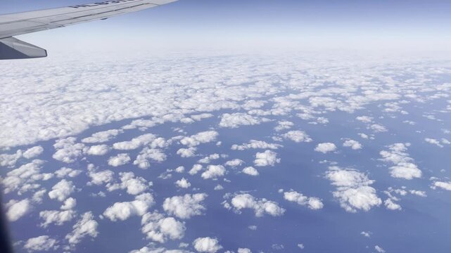 View from airplane flying above clouds &ndash; peaceful sky and soft sunlight over white cloudscape

