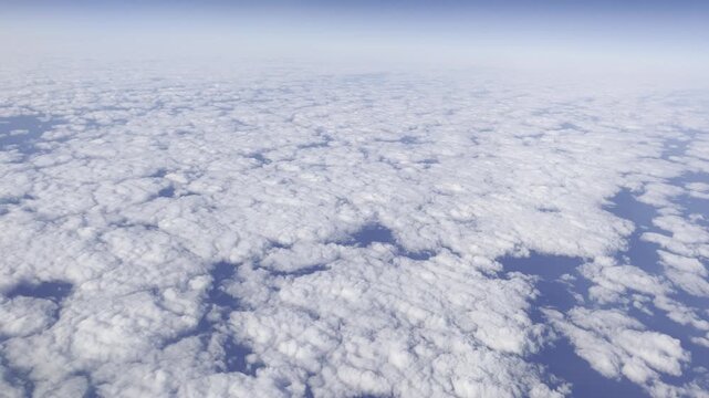 View from airplane flying above clouds &ndash; peaceful sky and soft sunlight over white cloudscape
