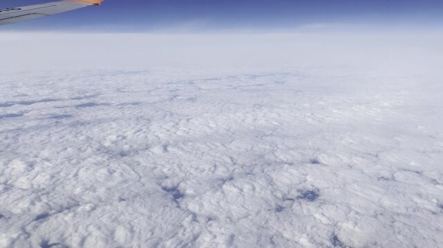 View from airplane flying above clouds &ndash; peaceful sky and soft sunlight over white cloudscape
