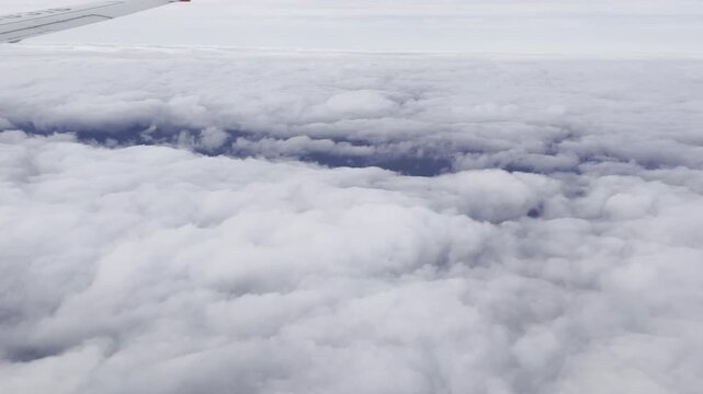 View from airplane flying above clouds &ndash; peaceful sky and soft sunlight over white cloudscape
